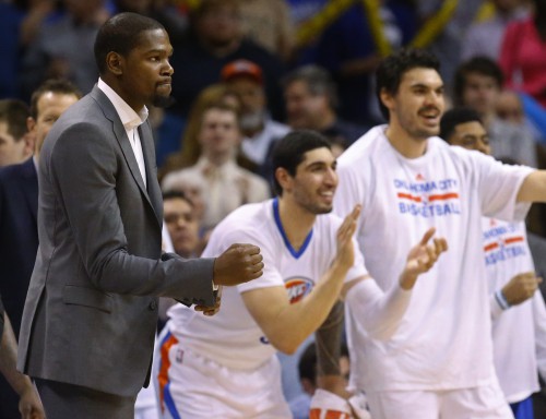 Injured Oklahoma City Thunder forward Kevin Durant, left, pumps his fist at teammates Enes Kanter, center, and Steven Adams, right, cheer in the fourth quarter of an NBA basketball game against the Toronto Raptors, Sunday, March 8, 2015, in Oklahoma City. Oklahoma City won 108-104. (AP Photo/Sue Ogrocki)